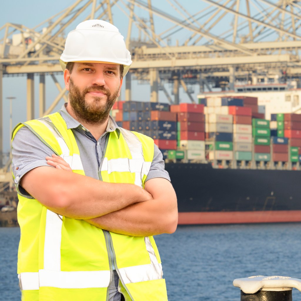 Safety officer at a port with container ship in background, indicates insurance plans for energy and logistics sectors