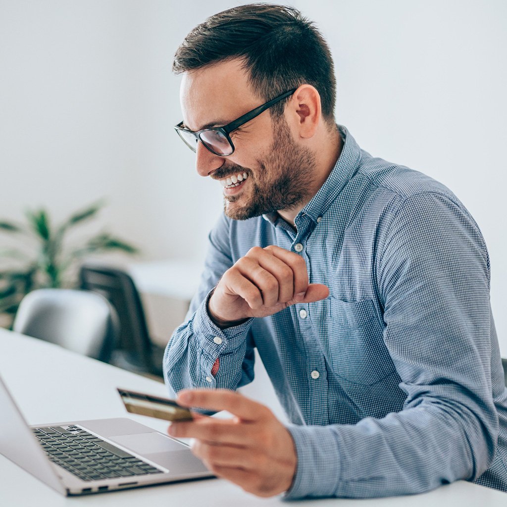 Smiling client holding a credit card while confidently completing a business life insurance purchase online